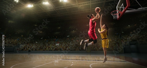 Obraz Female basketball players fight for the ball. Basketball player makes slam dunk on big professional arena during the game