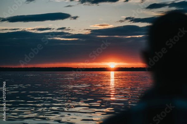 Fototapeta Weathered Man looking Towards a Sunset on a Sailboat