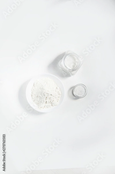 Fototapeta White plate with flour on a light background, a jar of sugar and a bowl of salt