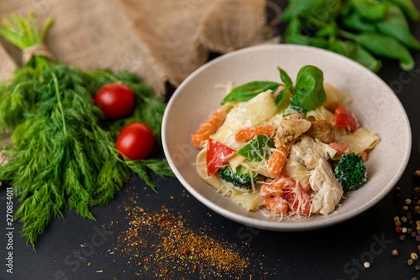 Obraz Farfalle pasta with tomatoes, garlic, broccoli, pesto sauce and grated parmesan cheese. Slow-mo.