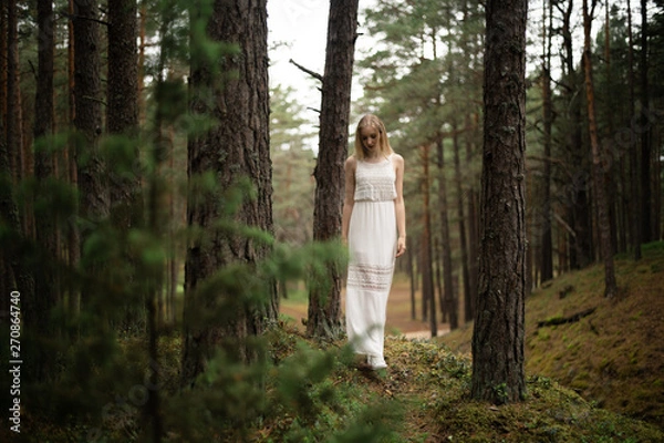 Fototapeta Walking Beautiful young blonde woman forest nymph in white dress in evergreen wood