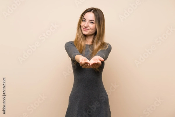 Obraz Young woman over isolated background holding copyspace imaginary on the palm to insert an ad