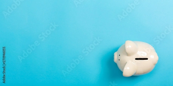Obraz A piggy bank saving and investment theme on a blue paper background
