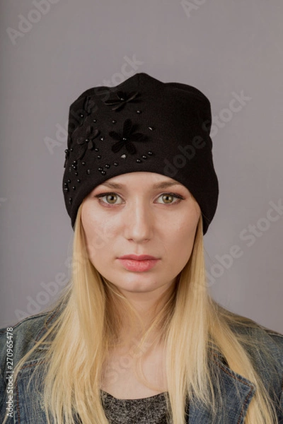 Fototapeta Portrait of a beautiful young girl in a stylish headdress with natural makeup on a gray background.