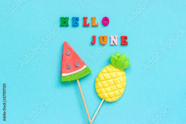 Obraz Hello June colorful text, pineapple and watermelon lollipops on stick on blue paper background. Concept vacation or holidays Creative Top view Template Greeting card, postcard