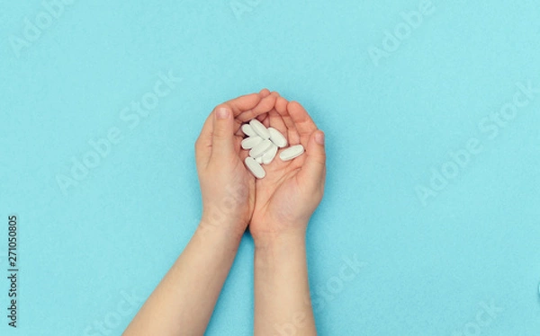 Obraz A small child holds a handful of white pills in their palms. The concept of healthy small children.