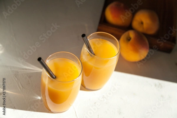 Fototapeta two peach juice glasses with shades