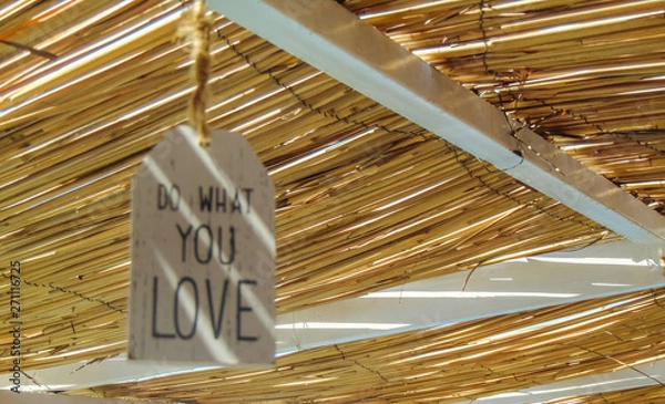 Obraz Do what you love inspirational quote hanging on the straw roof .