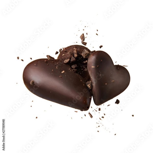 Fototapeta Two chocolate heart on a beige background. Hearts collide and break up into crumbs. High-speed shooting.