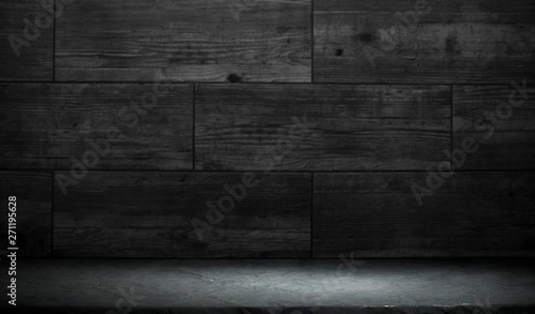 Obraz Old wood table with blurred concrete block wall in dark room background.