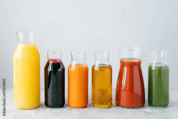 Fototapeta Refreshing summer drinks. Orange, carrot, apple, tomato, spinach and pomegranate juice in glass jars isolated over white background