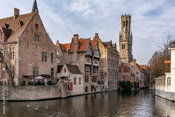 Fototapeta Bruges, Belgium - December 15, 2018: The Rozenhoedkaai (Quay of the Rosary) canal in Bruges with the classic medieval buildings and Belfry of Bruges in the background. Quay of Rosary in sunny day.