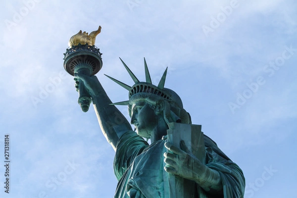 Fototapeta statue of liberty in new york with torch and tablet - close up from side with blue sky