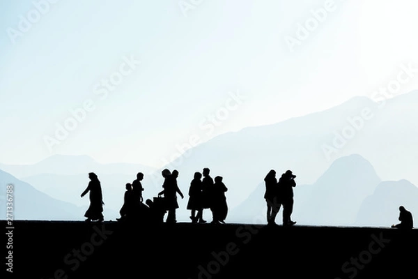 Fototapeta Silhouetted people walking and relaxing on street over sunny morning sky with high mountains in Antalya, Turkey
