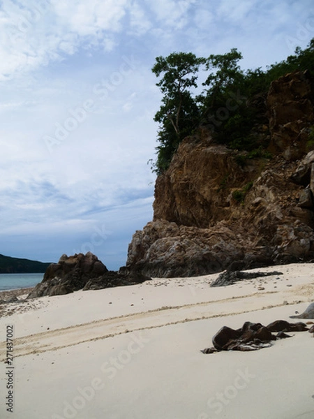 Fototapeta Large rock cliffs on the beach On the sky and clouds background