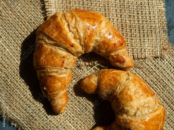 Fototapeta Fresh butter croissants on a mat that is placed on a dark gray wood table