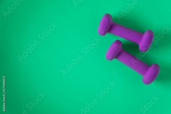 Fototapeta Fitness equipment with womens purple weights/ dumbbells isolated on a teal green background with copyspace