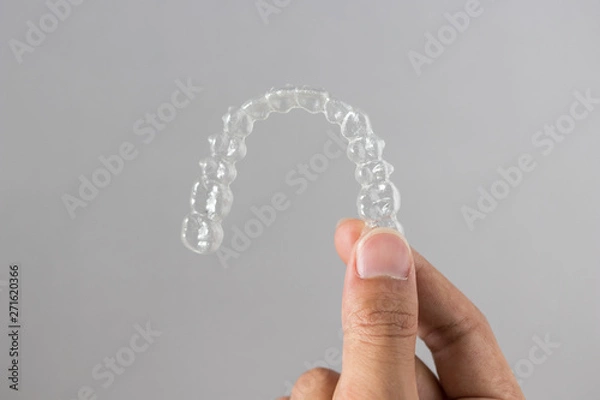 Obraz Holding invisalign braces or invisible retainers on grey background, new orthodontic equipment