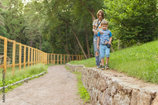 Fototapeta Mom and son go in the woods in the summer.