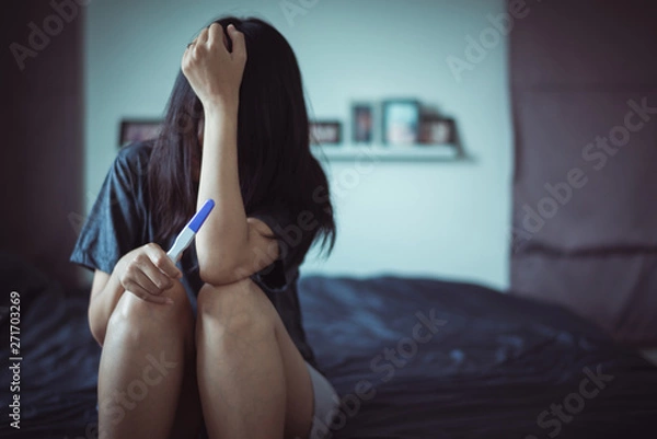 Obraz Asian depressed woman sitting in her bedroom after testing pregnancy test