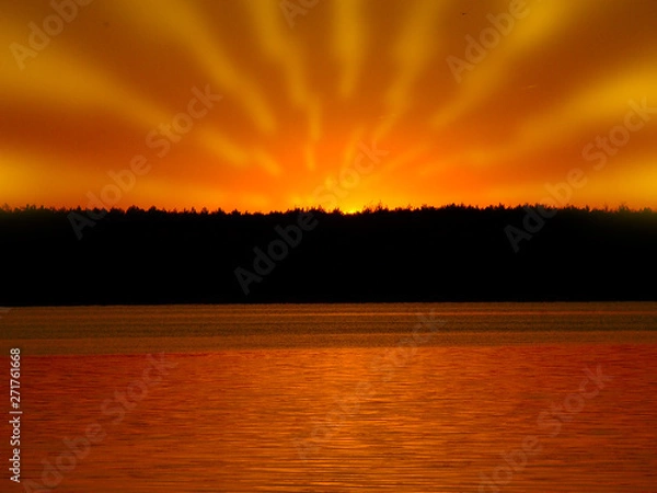 Obraz Orange light with sun rays and dark forest on river