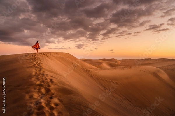 Fototapeta young woman from behind walking in sand dunes of maspalomas, gran canaria