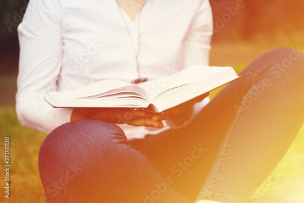 Fototapeta Exchange student , holding notebook, thinking on project.  walking and talking each other in a campus at sunset with a warm light