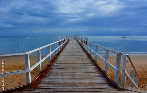 Fototapeta Great views of Hervey Bay from the wooden Torquay jetty. The pier is also a popular fishing spot at all tides. Gushing sea on a cloudy day. Horizontal view of dramatic overcast sky and sea.