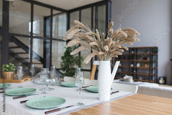 Fototapeta A vase with dry flowers on a table. Scandinavian classic kitchen with wooden and white details, minimalistic interior design. Real photo.Cosy home.