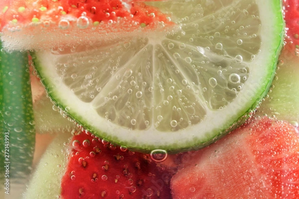 Fototapeta Refreshing fruit sparkling water from strawberries and lime in a glass mug close-up, background.