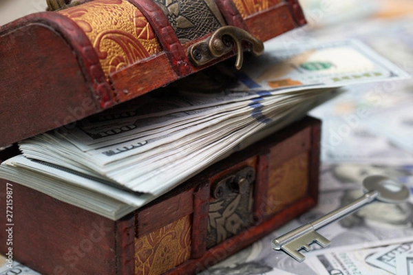 Obraz A full chest with dollar bills. Dollars bils background and silver key. Close up