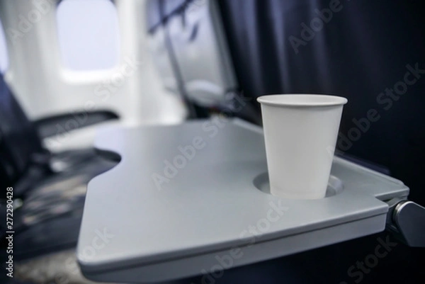 Fototapeta plastic cup on the table in the plane during the flight. alcohol consumption on board