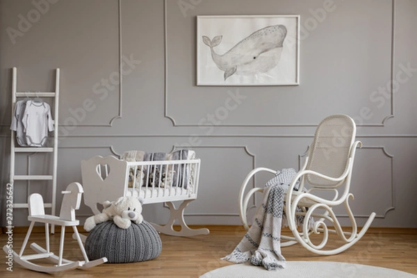 Fototapeta Grey whale on poster in classy baby room interior with white wooden rocking chair, rocking horse, crib and scandinavian ladder, copy space on empty wall