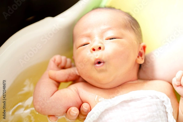 Fototapeta 薬草の煎じ汁を入れたお風呂に浸かる生後2週間の赤ちゃん