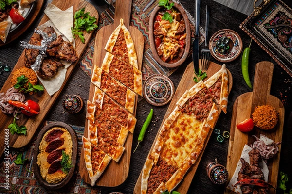 Obraz Traditional Turkish cuisine. Pizza, pita, pidesi, sucuk, hummus, kebab, bulgar. Many dishes on the table. Serving dishes in restaurant. Background image. Top view, flat lay