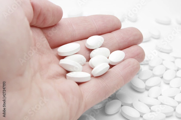 Obraz Pills in male palm over white table