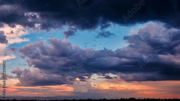 Fototapeta Dramatic light through the clouds against the backdrop of an exciting, bright stormy sky at sunset. panorama, natural composition