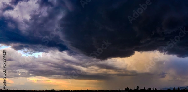 Fototapeta Dramatic light through the clouds against the backdrop of an exciting, bright stormy sky at sunset. panorama, natural composition