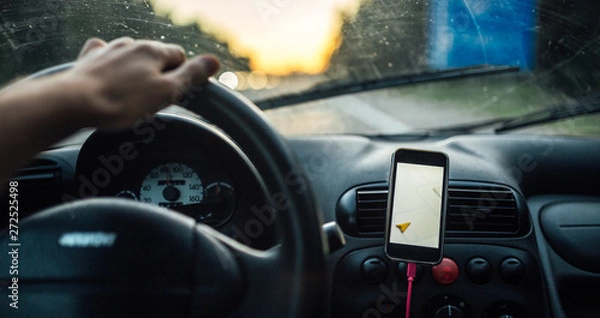 Fototapeta travel driving a car in the summer, the navigator in the smartphone. the driver is driving