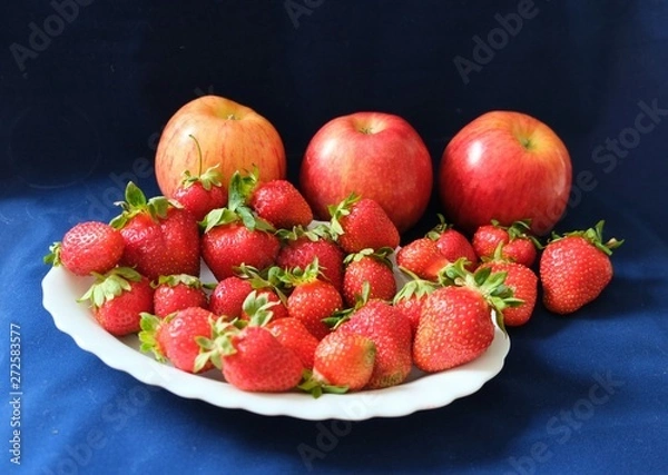 Fototapeta ripe strawberries and red apples on a blue background