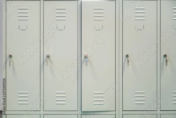Fototapeta A row of grey metal school lockers with keys in the doors