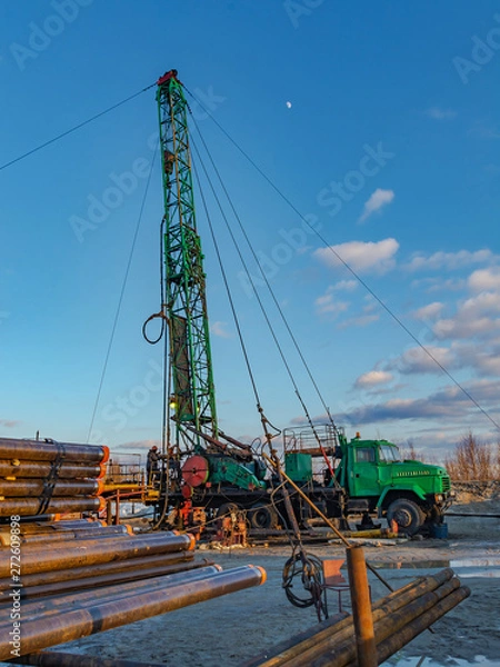Fototapeta Mobile rig for the repair of deep oil wells in the field. Drilling and casing pipes are stored in the foreground.