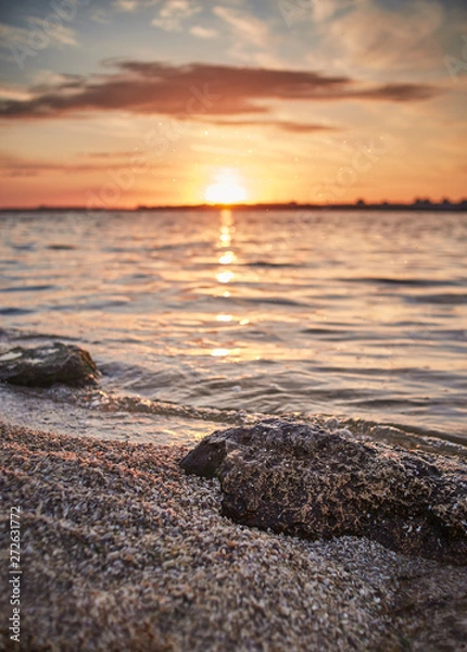Fototapeta sunrise on the beach with the stone in focus
