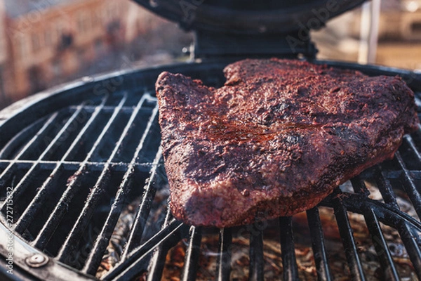 Fototapeta Close up on the blackened and charred bark of a smoked beef brisket, in a slow cooking background