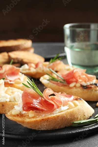 Obraz Tasty bruschettas with prosciutto and cream cheese served on table, closeup