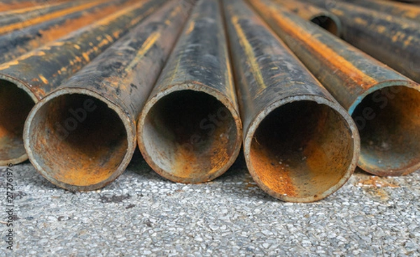 Obraz rusted construction pipe laid on asphalt 