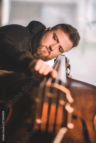 Obraz Young luthier working in his workshop, building a double bass