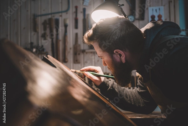 Fototapeta Young luthier working in his workshop, building a double bass