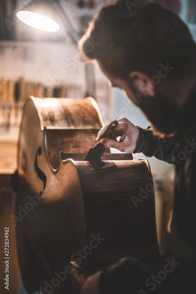 Obraz Young luthier working in his workshop, building a double bass