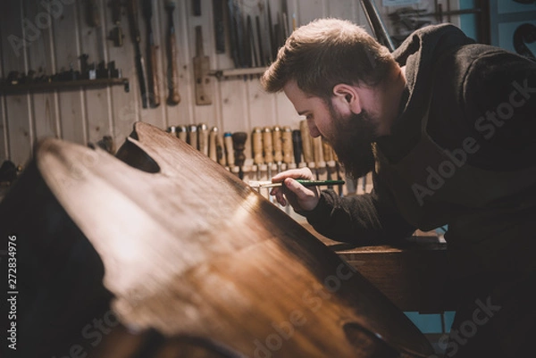 Obraz Young luthier working in his workshop, building a double bass